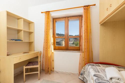 ein Schlafzimmer mit Bett, Schreibtisch und Fenster in der Unterkunft Casa a due passi dal mare in Àrbatax