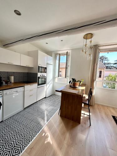 une cuisine avec des armoires blanches et une table en bois dans l'établissement Rue Marceau Cogolin, à Cogolin