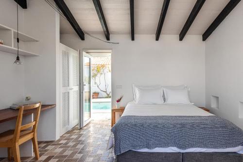 a bedroom with a bed and a table and a window at Sanderling beach & dune house in Carrapateira