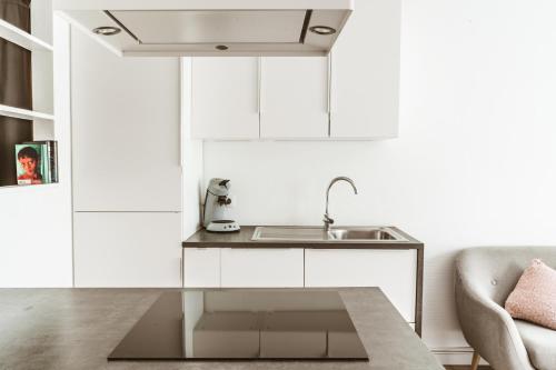 a white kitchen with a sink and a couch at Luxe studio in Ostend