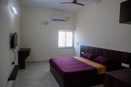 a bedroom with a bed with purple sheets and a window at Varshini Palace in Tirumayam