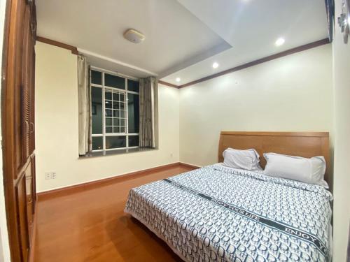 Schlafzimmer mit einem Bett und einem Fenster in der Unterkunft Căn hộ Hoàng Anh DakLak ngay trung tâm BMT gồm 3PN lớn Full nội thất rộng rãi từ 8-10 người in Buon Ma Thuot