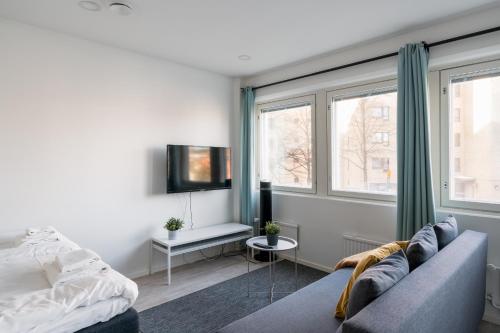 a bedroom with a bed and a couch and windows at Hiisi Homes Helsinki Haaga in Helsinki
