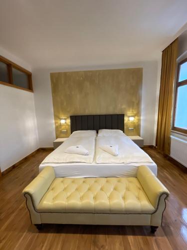 een slaapkamer met een bed en een gele bank bij Pension & Restaurant Atmosféra in Loket