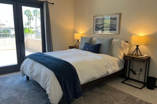 a bedroom with a bed with two lamps and a window at The Arrowhead Oasis - hot tub, heated pool, fire pits, backyard games in Glendale