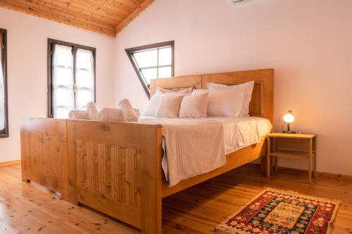 Un dormitorio con una gran cama de madera con almohadas blancas. en Porta7 Hotel en Gjirokastër