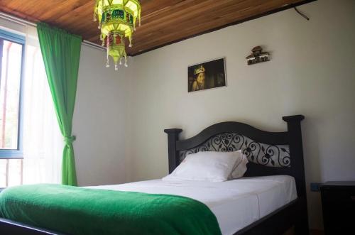 1 dormitorio con 1 cama con manta verde y lámpara de araña en Hab doble & baño privado, en Armenia