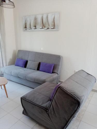 a living room with a couch with purple pillows at Deaspoina Apartments in Nea Roda
