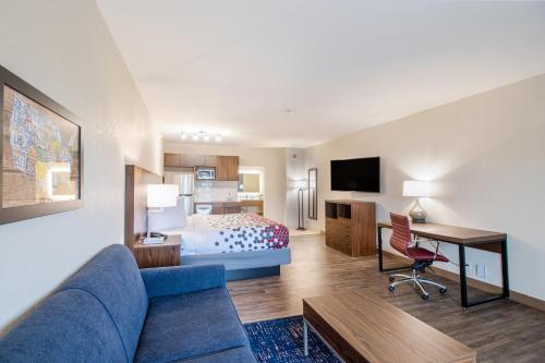a hotel room with a bed and a blue couch at Econo Lodge Inn & Suites Foley-North Gulf Shores in Foley