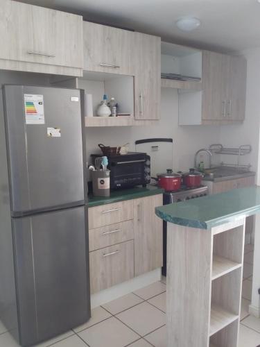 La cuisine est équipée d'un réfrigérateur en acier inoxydable et de placards en bois. dans l'établissement Departamento Ciudad del Encanto, à Ovalle