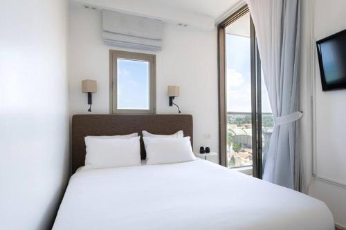 a bedroom with a white bed and a large window at Sea View Heaven by Five Stay in Herzliya B