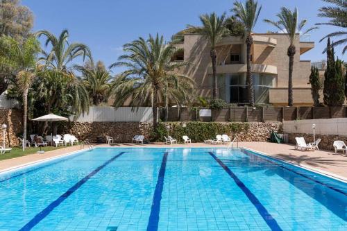a swimming pool in front of a building with palm trees at Sea View Heaven by Five Stay in Herzliya B