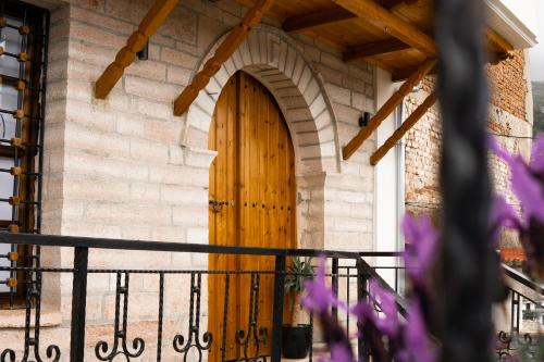 una porta in legno su un edificio in mattoni con fiori viola di Porta7 Hotel a Gjirokastër