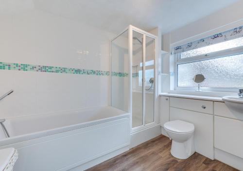 謝林漢姆的住宿－3 Hilbre Court，白色的浴室设有浴缸、卫生间和水槽。
