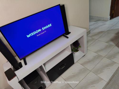 TV de pantalla plana en un soporte de TV blanco en Rovers Apartment en Nanyuki