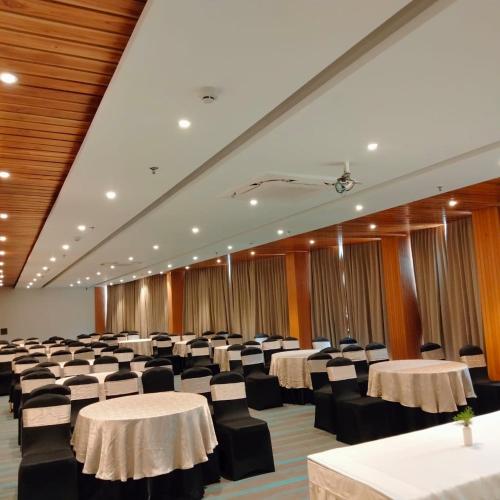 a banquet hall with white tables and black chairs at Rosetum Kasauli in Kasauli
