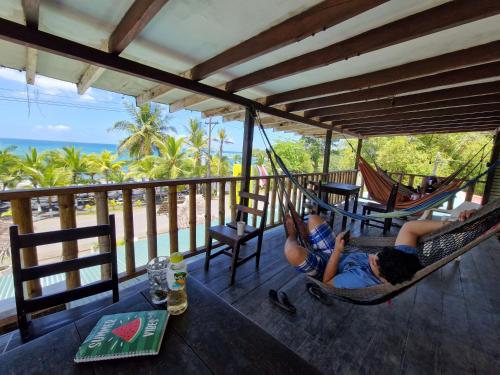 a woman laying in a hammock on a porch at Playa Negra Brewing Beachfront Hotel in Puerto Viejo