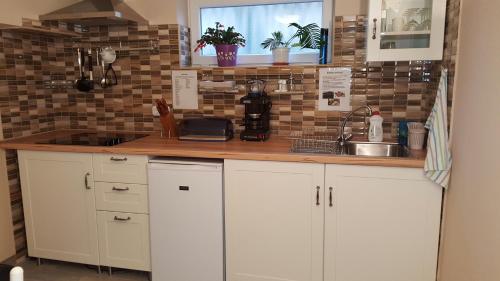 a kitchen with white cabinets and a sink at Kitti Panzió in Mogyoród