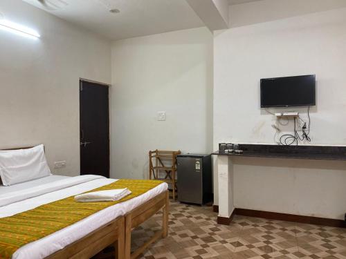 a bedroom with a bed and a tv on the wall at Calangute Beach Palms in Calangute