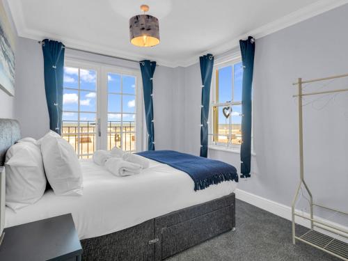 um quarto com uma cama com cortinas azuis e janelas em Pass the Keys Sunset Cottage Luxury Home On The Seafront em Herne Bay