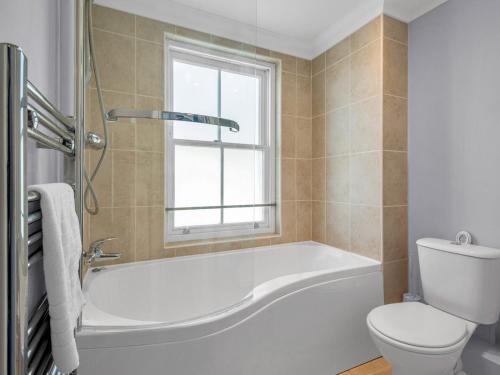 a bathroom with a tub and a toilet and a window at Pass the Keys Sunset Cottage Luxury Home On The Seafront in Herne Bay