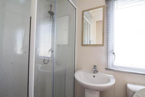 a white bathroom with a sink and a shower at Lovely 6 Berth Caravan For Hire In Norfolk, By A Beautiful Beach! Ref 50030j in Great Yarmouth