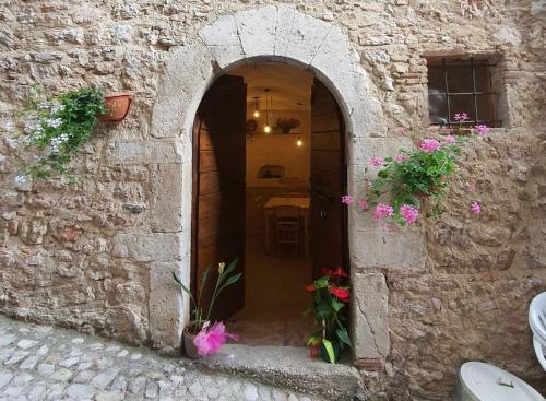 an archway in a stone building with flowers at Il borgo di Cornillo in Meggiano