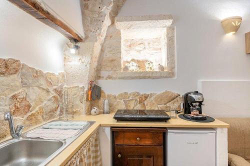 a kitchen with a sink and a stone wall at La Nicchia di Zio Valerio in Ceglie Messapica