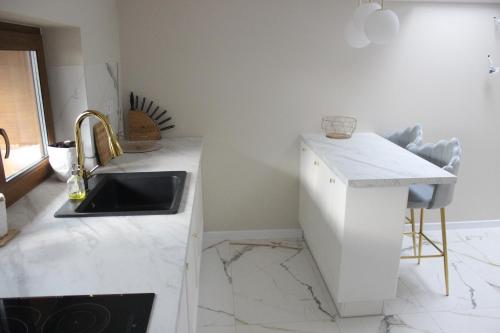 a white kitchen with a sink and a counter at Apartament na Helskiej in Rewa