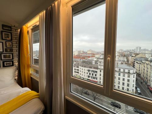een kamer met een raam met uitzicht op de stad bij Appartement Flandre in Parijs