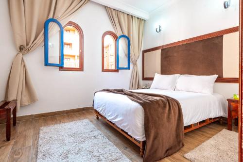a bedroom with a large bed and two windows at Hotel Oudaya & Spa in Marrakech