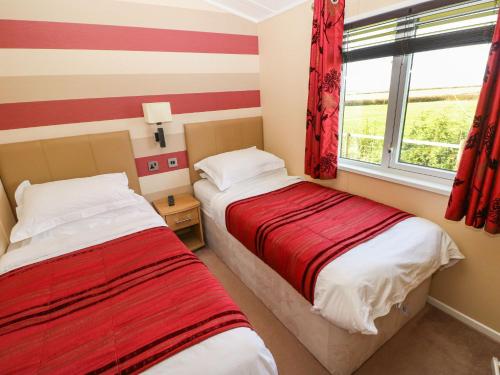 two beds in a room with red and white stripes at Mountain View Lodge in Whitland
