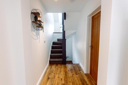 a staircase in a home with white walls and wood floors at Chute House 4 bed house private garden city center in Exeter