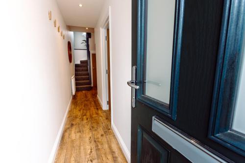 a hallway with a black door and a wooden floor at Chute House 4 bed house private garden city center in Exeter