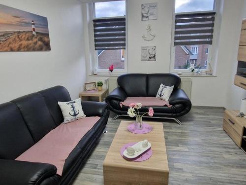 una sala de estar con 2 sofás de cuero negro y una mesa. en Küstenliebe, en Bremerhaven