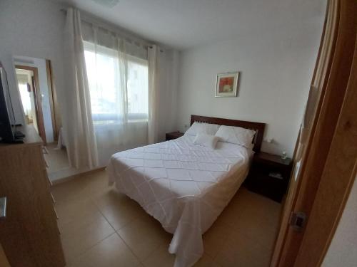 1 dormitorio con cama blanca y ventana en Luxury South Facing Golf Course Apartment & Pool in Roldan, en Las Pedreñas