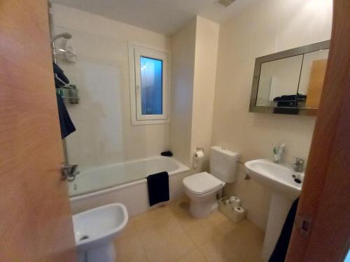 y baño con bañera, aseo y lavamanos. en Luxury South Facing Golf Course Apartment & Pool in Roldan, en Las Pedreñas