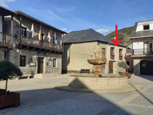 a fountain in front of a building with flags at www luabierzo in Molinaseca