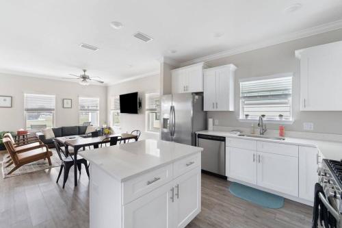 a kitchen with white cabinets and a table and a dining room at Downtown home + bay views + seafood market in Pensacola