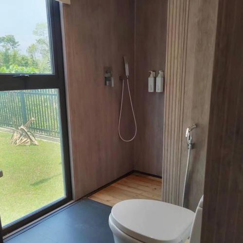 a bathroom with a toilet and a window at My Excel Garden Mini Glass Villa with Forest View in Air Hangat