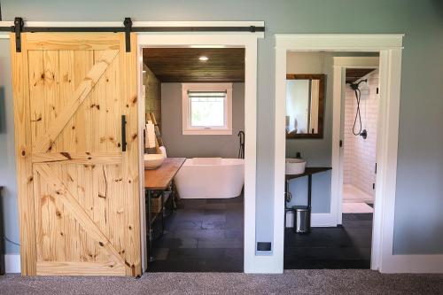 Modern Industrial Farmhouse - The Wayback في Orange: حمام به باب خشبي وحوض استحمام