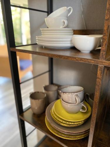 a shelf with plates and cups and dishes on it at Das Krimihaus Ostfriesland in Rhauderfehn