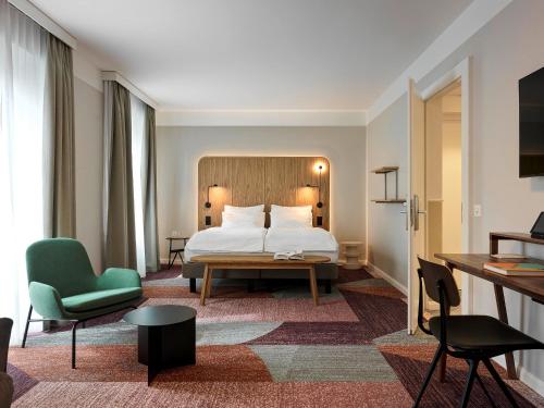 チューリッヒにあるホテル セント ジョセフのベッドと緑の椅子が備わるホテルルームです。