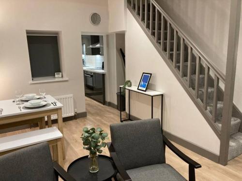 a living room with a staircase and a table and chairs at Stunning Coastal Retreat in Carrickfergus
