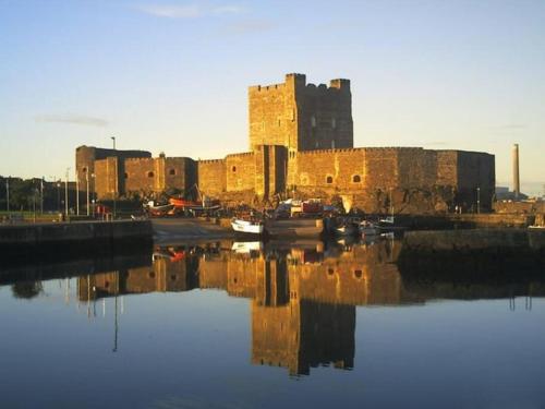 a view of a castle with boats in the water at Stunning Coastal Retreat in Carrickfergus