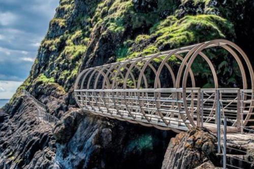 Stunning Coastal Retreat في كاريكفرغس: جسر معدني فوق جبل صخري