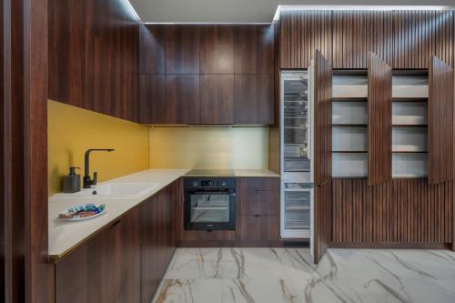 a kitchen with wooden cabinets and a sink and a stove at Mickiewicza Prestige Residence with Parking by Rentujemy Łódź City Center in Łódź