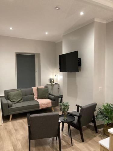 a living room with a couch and a tv on a wall at Stunning Coastal Retreat in Carrickfergus