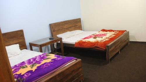 a room with two beds and a table with two beds at Rakaposhi Amin Hotel & Restaurant Pissan Hunza Nagar Gilgit Baltistan in Gilgit