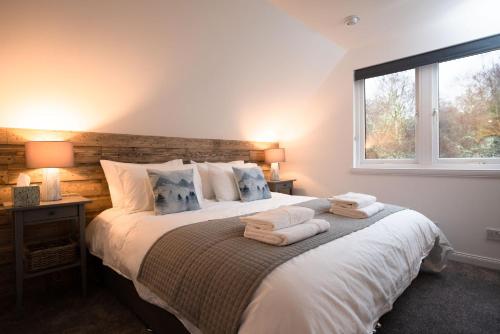 1 dormitorio con 1 cama grande y toallas. en The Wilds - Seasgair Lodges en Kingussie